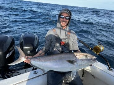 Angler displaying a large Halibut while fishing on a boat in open waters.