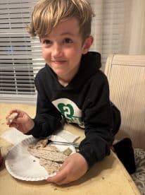 A young boy enjoying a meal with fish on a plate, showcasing a casual dining experience.