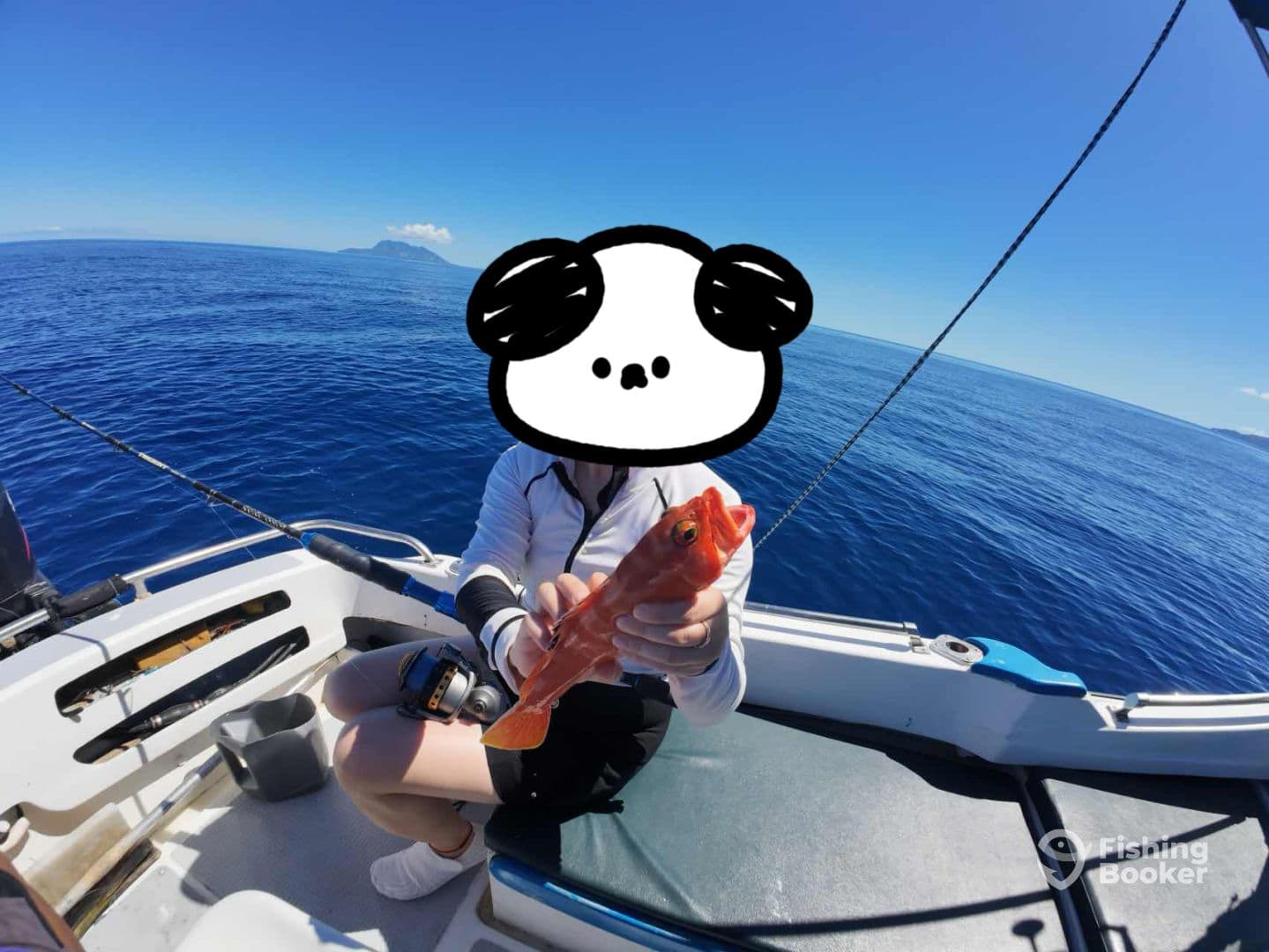 An angler proudly displaying a vibrant red fish while fishing on a clear day in open waters.
