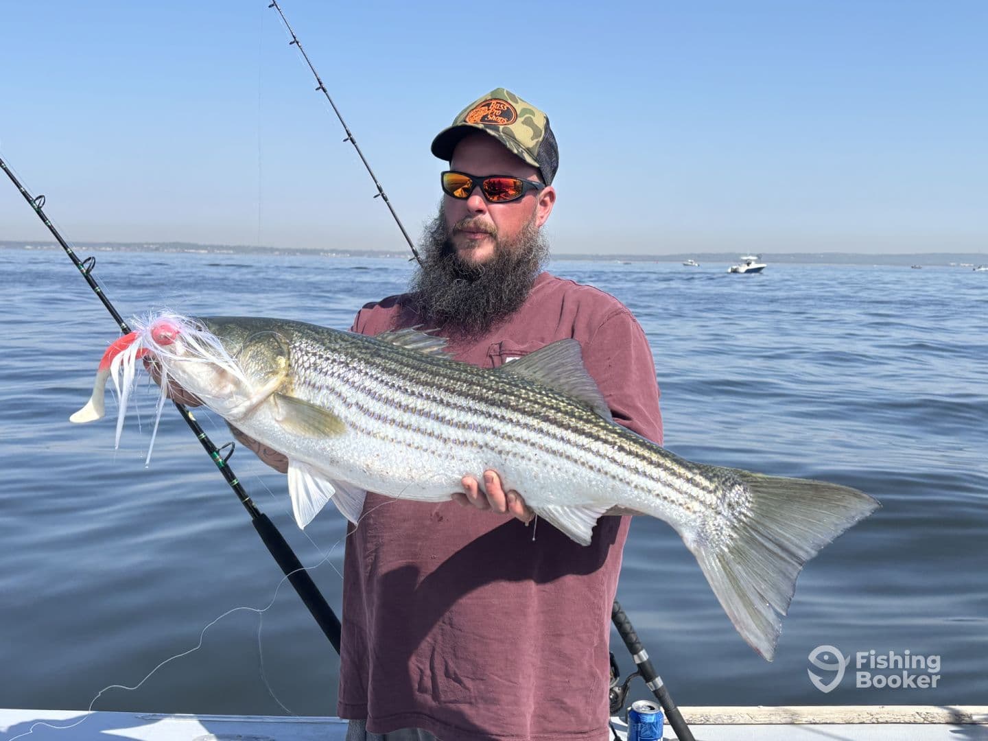 An angler proudly displaying a large Striped Bass while fishing on a clear day, showcasing the excitement of a successful catch.