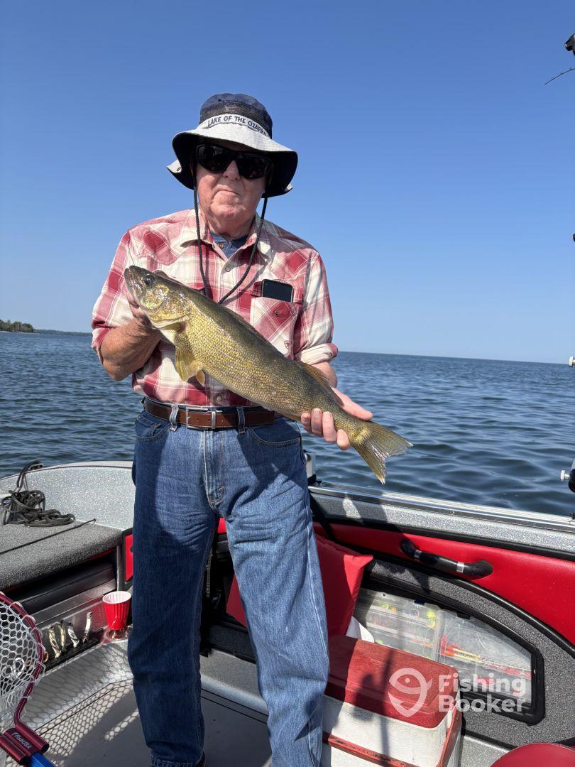 An angler proudly displaying a Walleye while fishing on a sunny day at Lake of the Ozarks, showcasing a successful catch from a boat.
