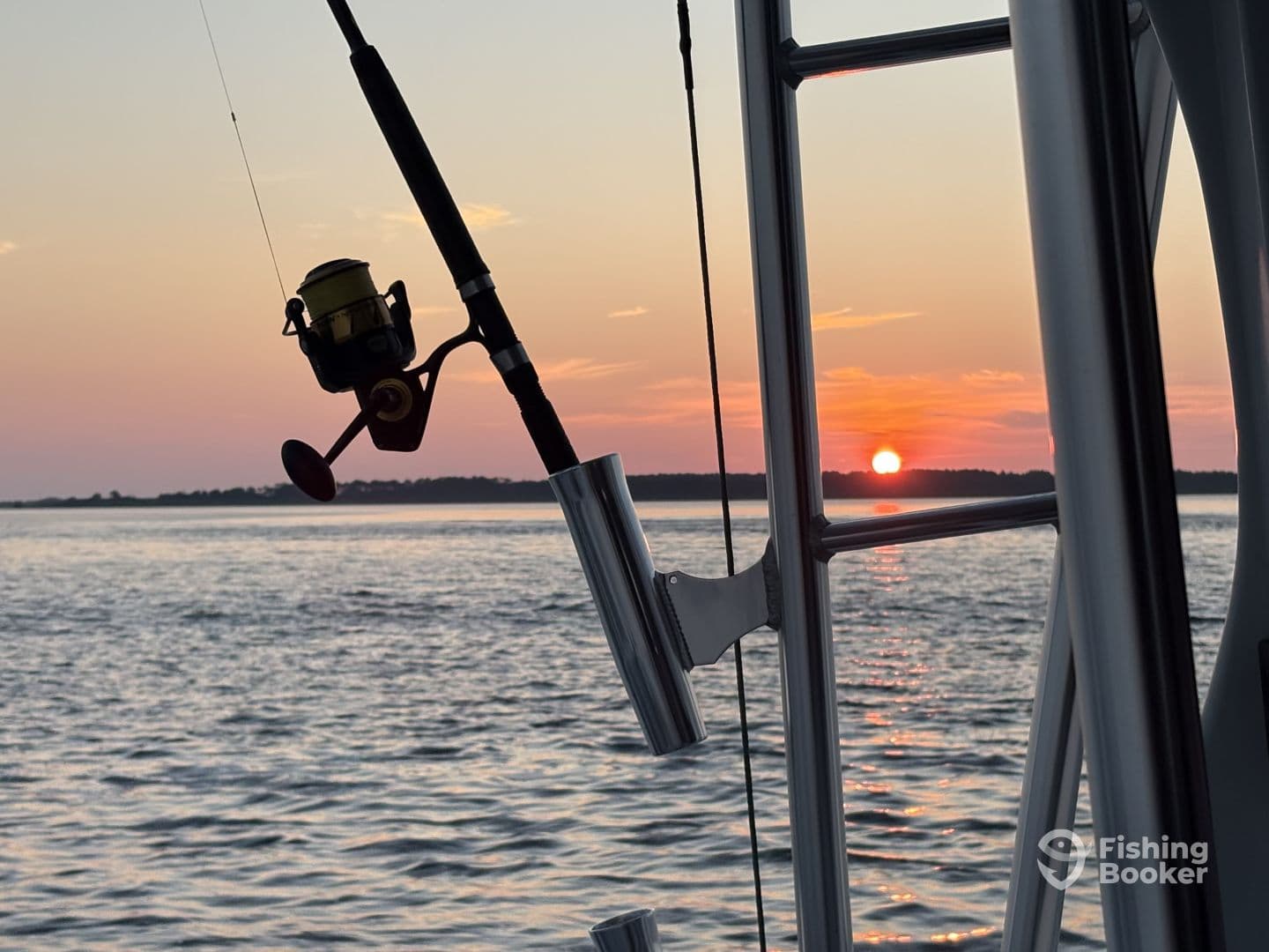 A scenic view from a fishing boat at sunset, featuring a fishing rod and reel silhouetted against the colorful sky.