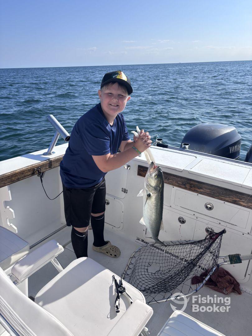 A young angler proudly displaying a caught fish aboard a boat, enjoying a day of fishing on the open water.