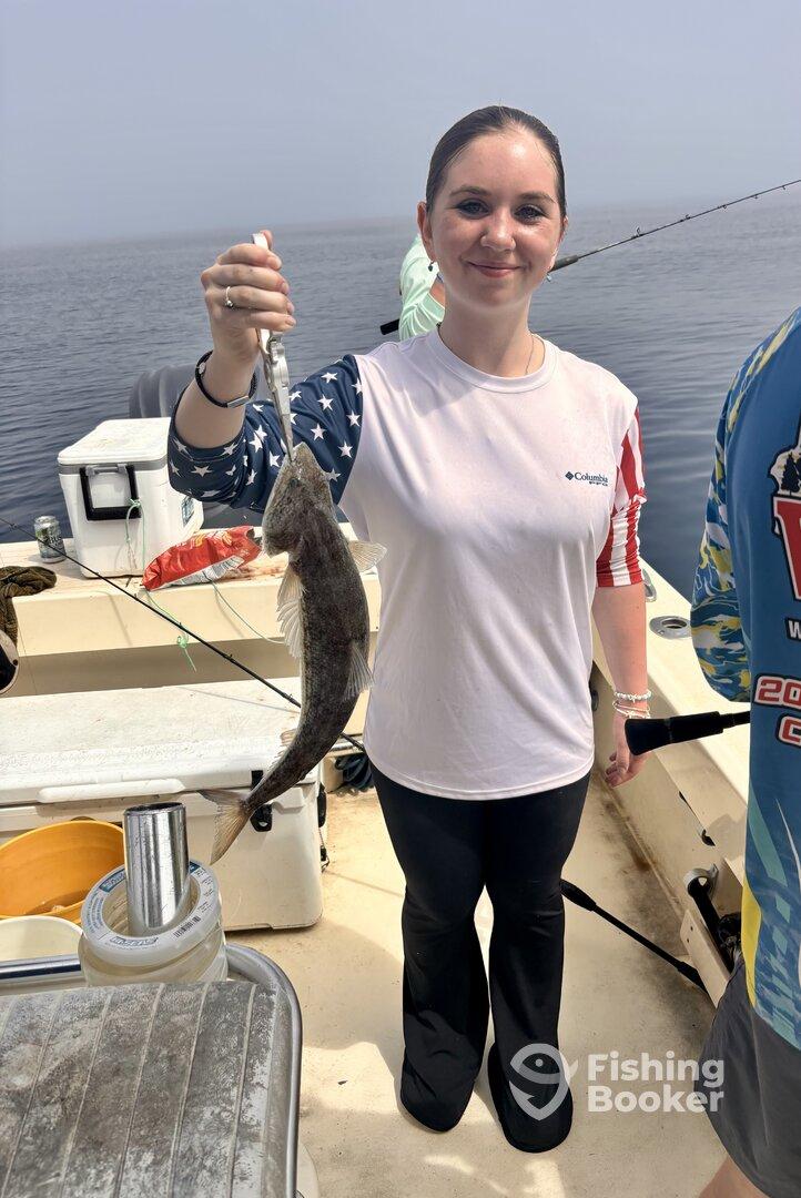 A young angler proudly displaying a caught fish while fishing on a boat, showcasing a successful day on the water.