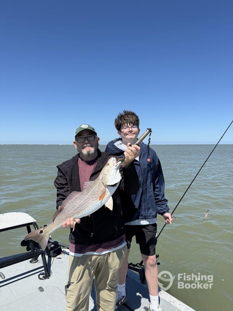 A proud moment for a family as they showcase a large Redfish caught during their fishing trip.
