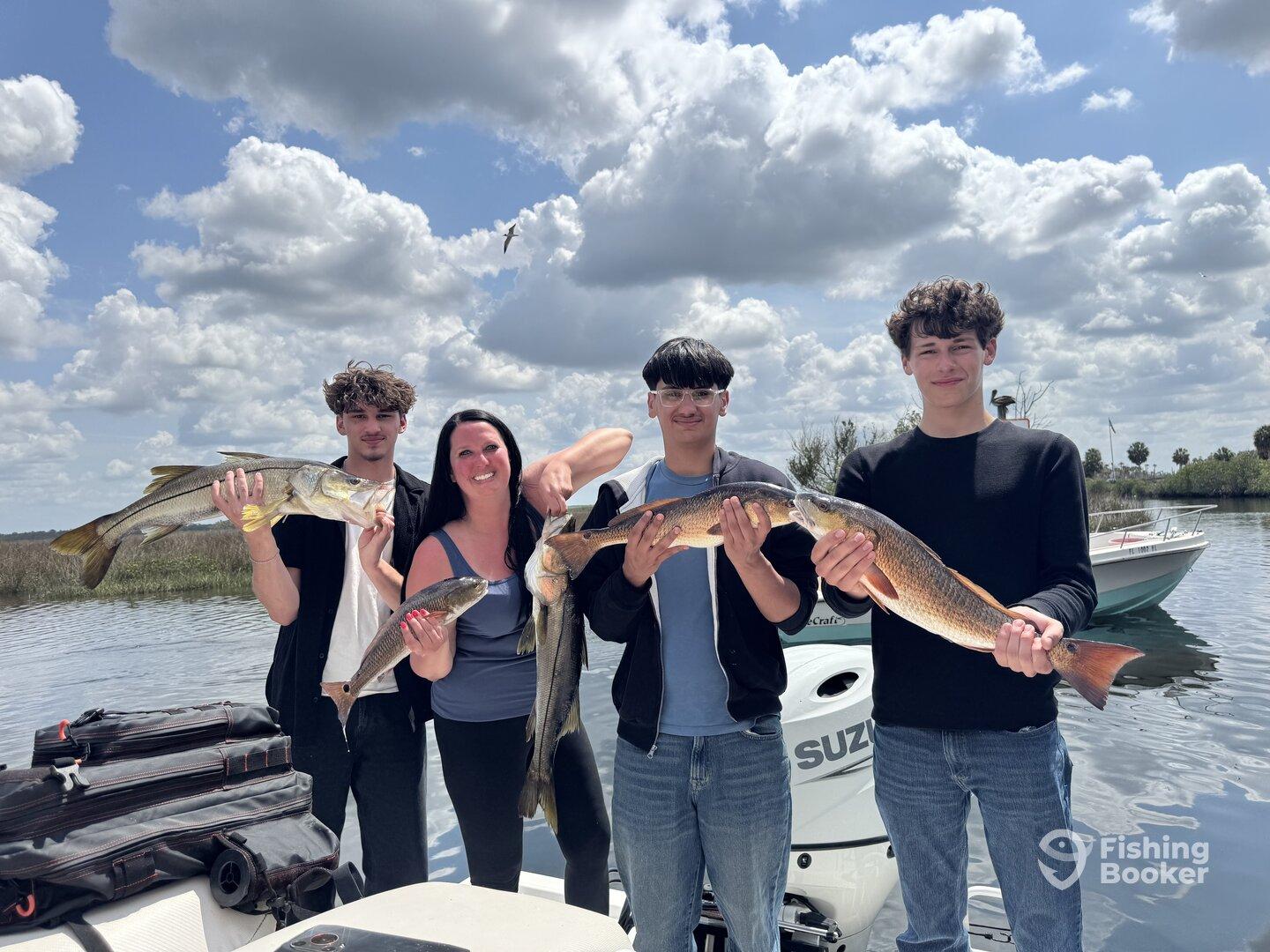 A family proudly displaying their catch of Snook and Redfish while enjoying a day on the water.