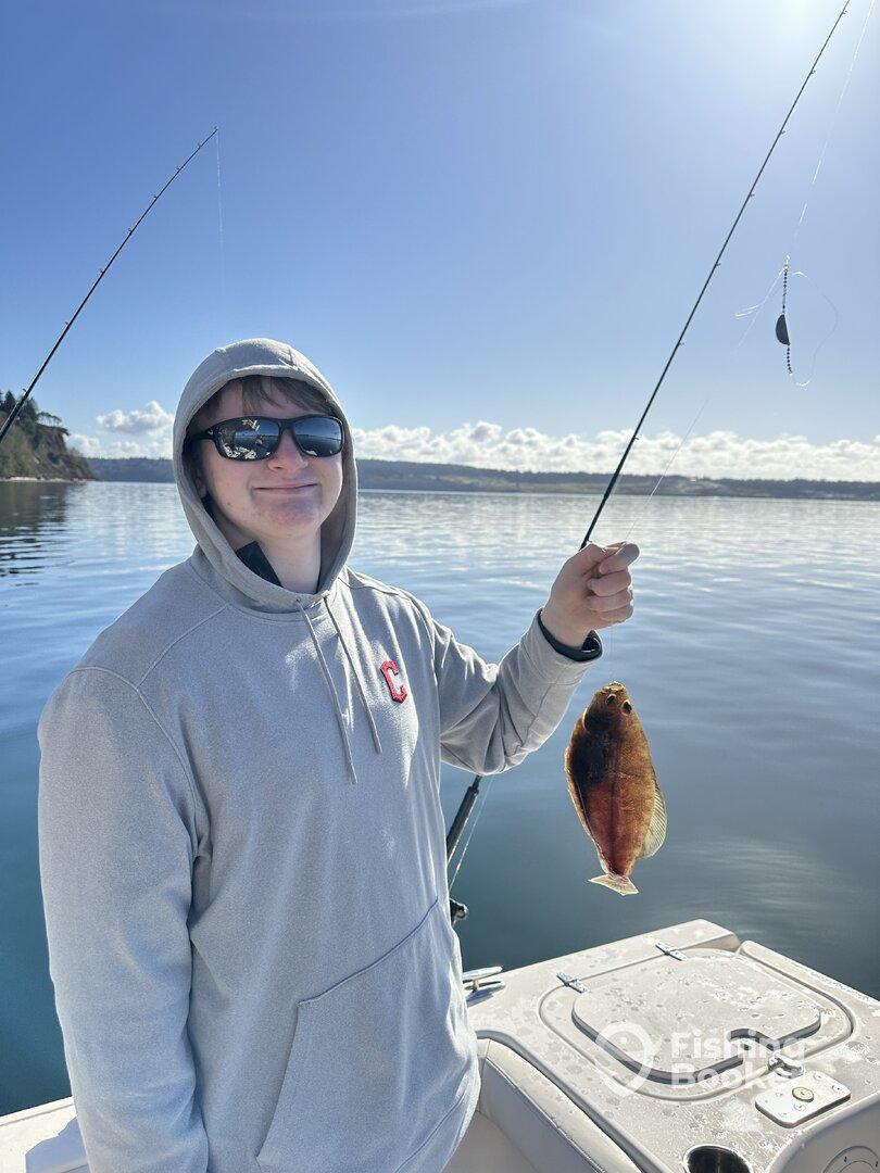Young angler proudly holding a flatfish while fishing on a calm day, showcasing a successful catch.