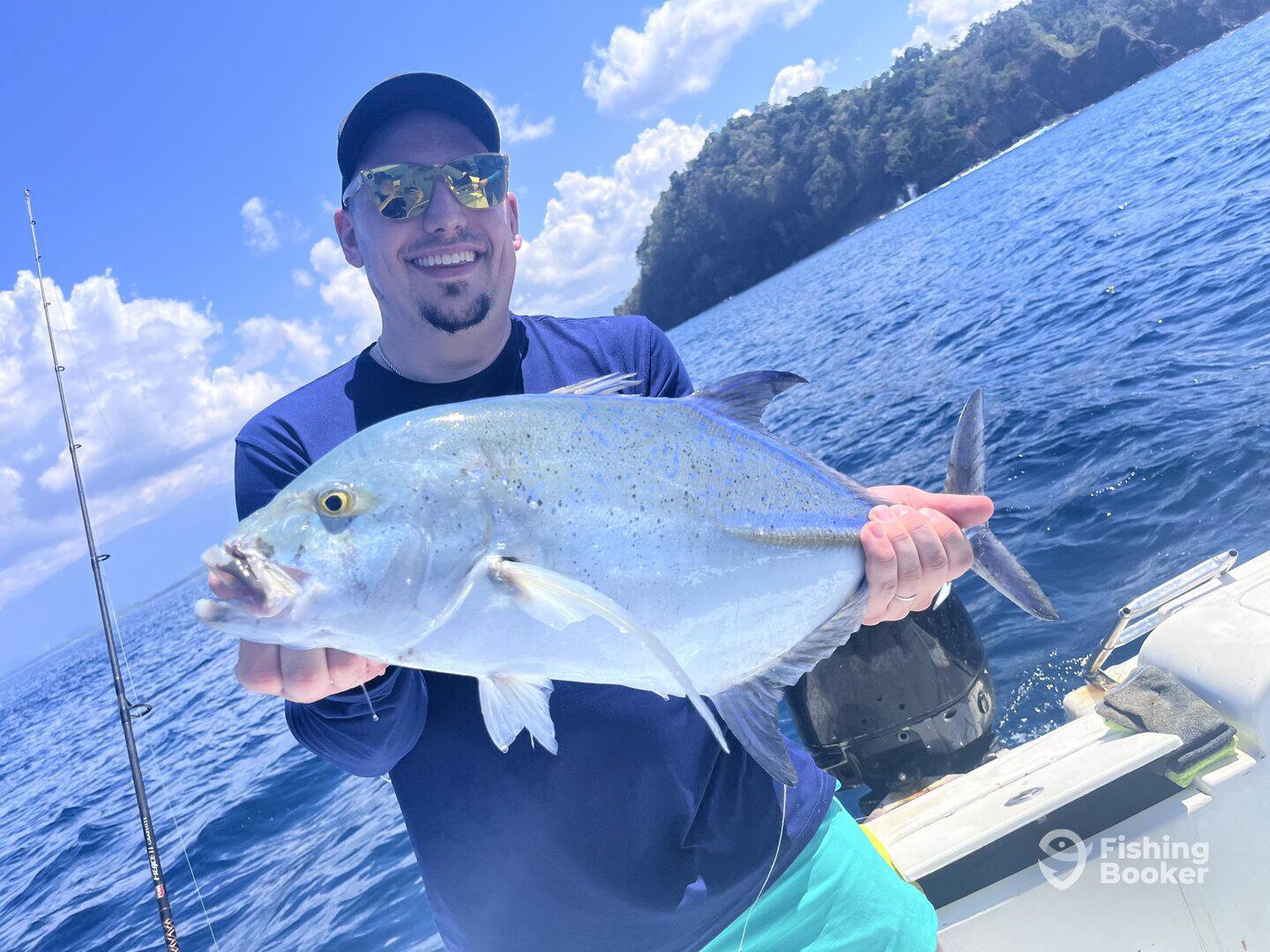 Angler proudly displaying a large fish while fishing in a scenic ocean environment.