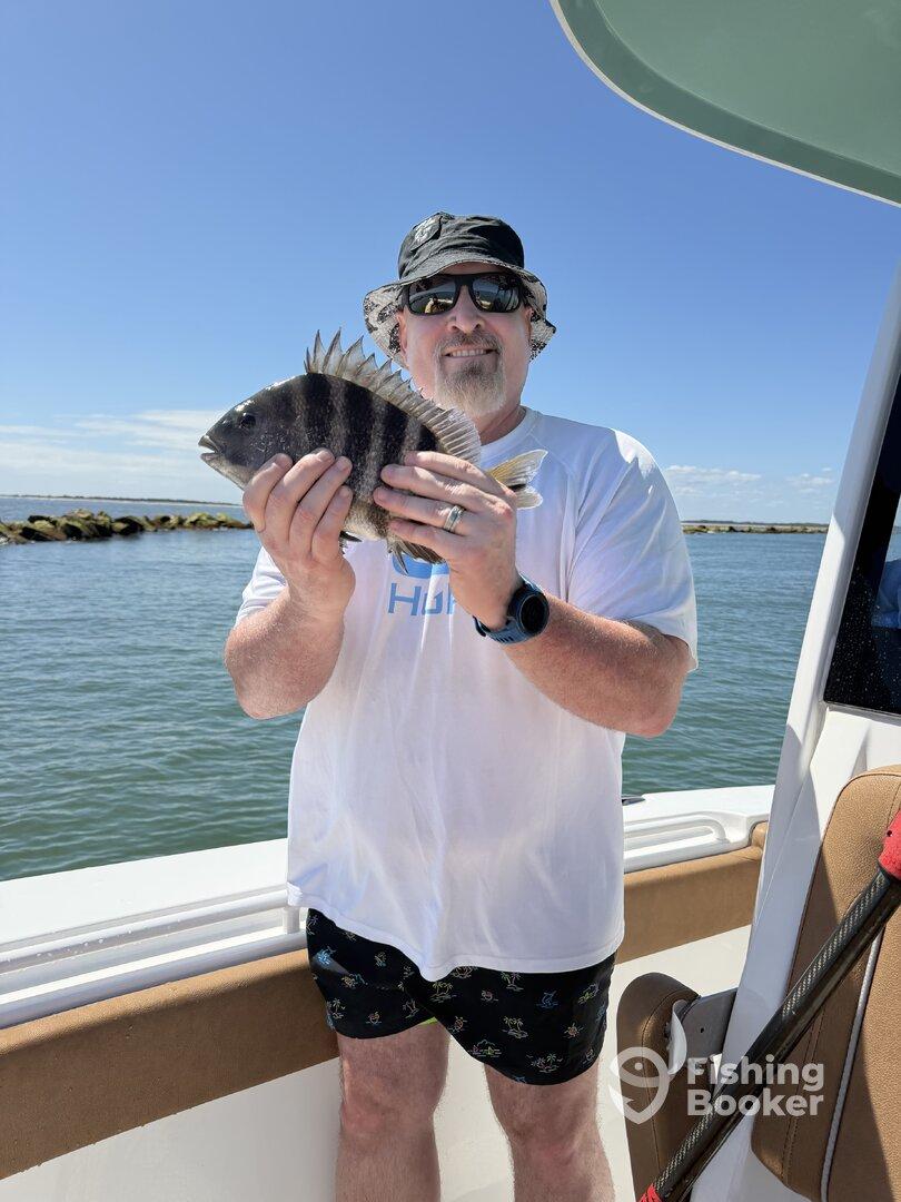 An angler proudly displaying a Sheepshead fish while enjoying a sunny day on the water.