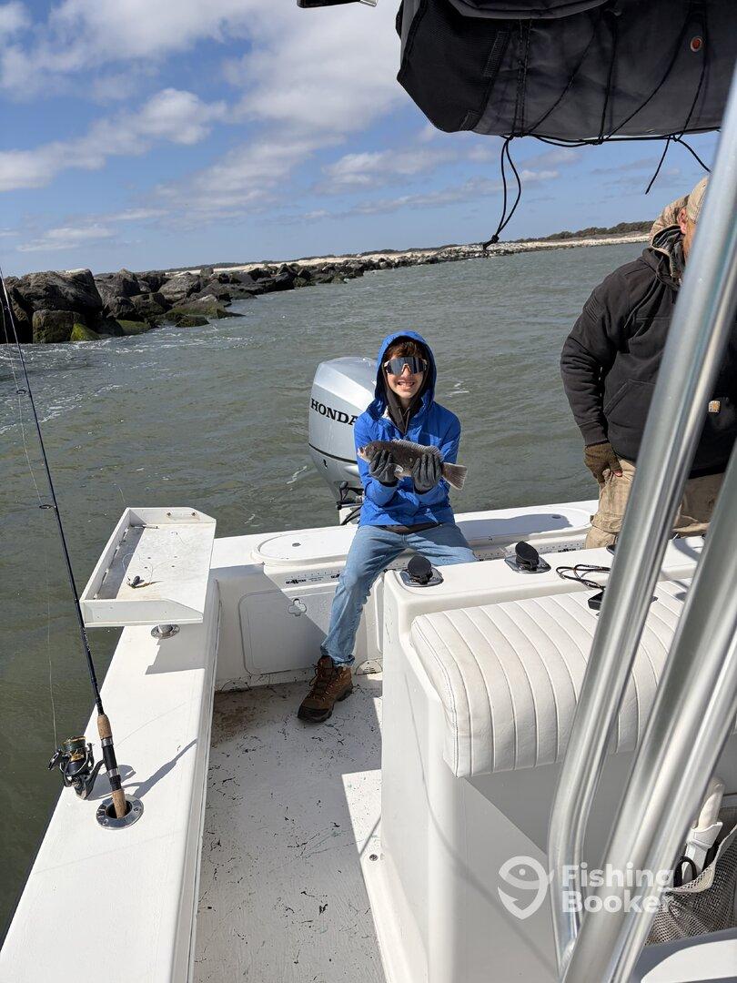 A young angler proudly displaying a caught fish while aboard a fishing boat, enjoying a day on the water.