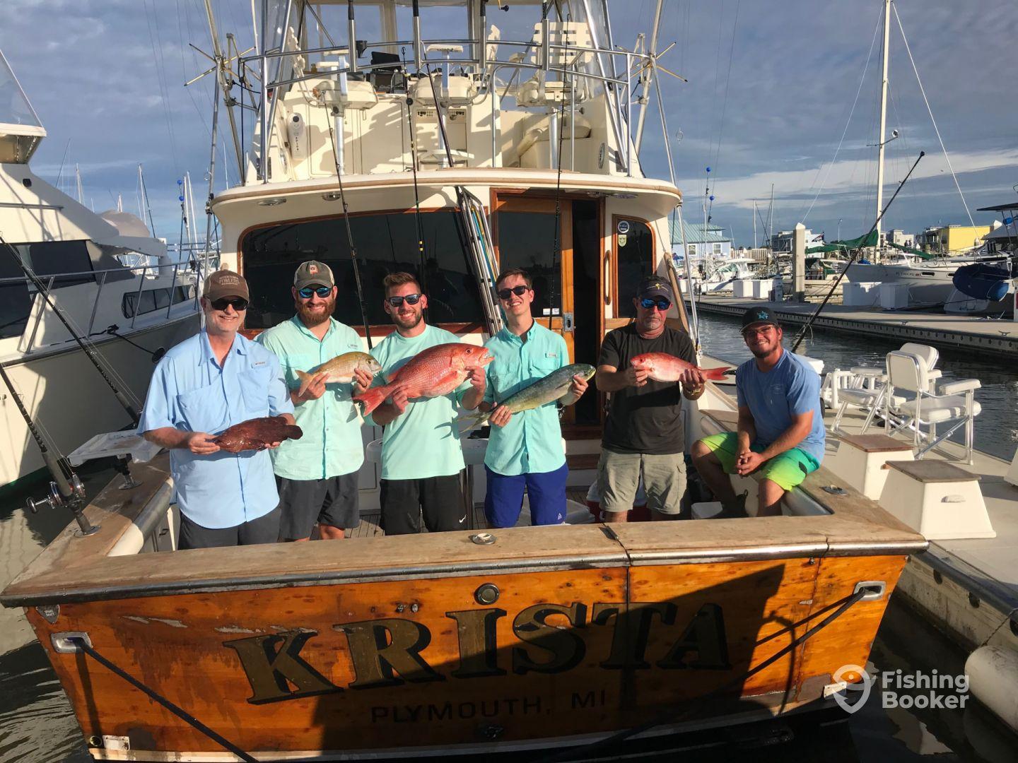 A group of anglers proudly displaying their catch of colorful Snapper and a Mahi Mahi aboard the 'Krista' after a successful fishing trip in Plymouth, MI.