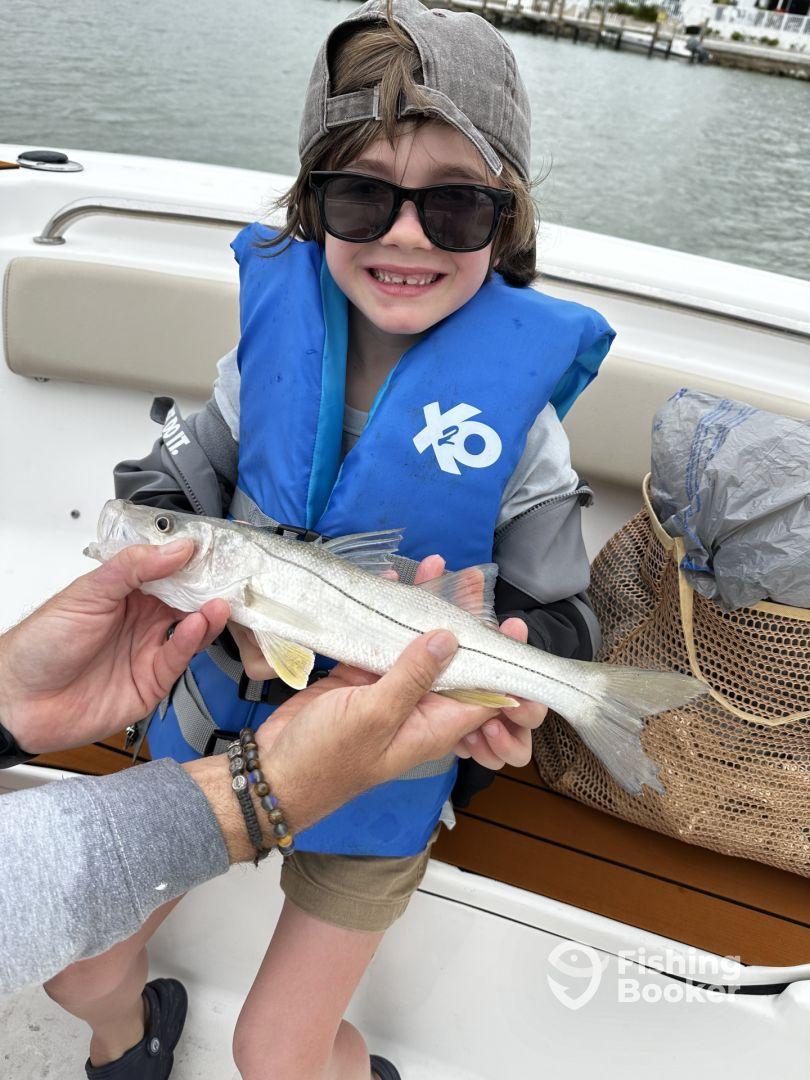 A young angler proudly displaying a caught fish while on a boat, showcasing a fun family fishing experience.