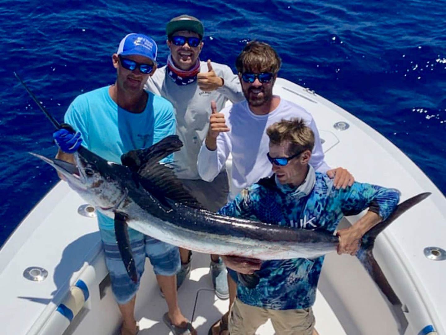 Cuatro pescadores sosteniendo un Blue Marlin en un bote