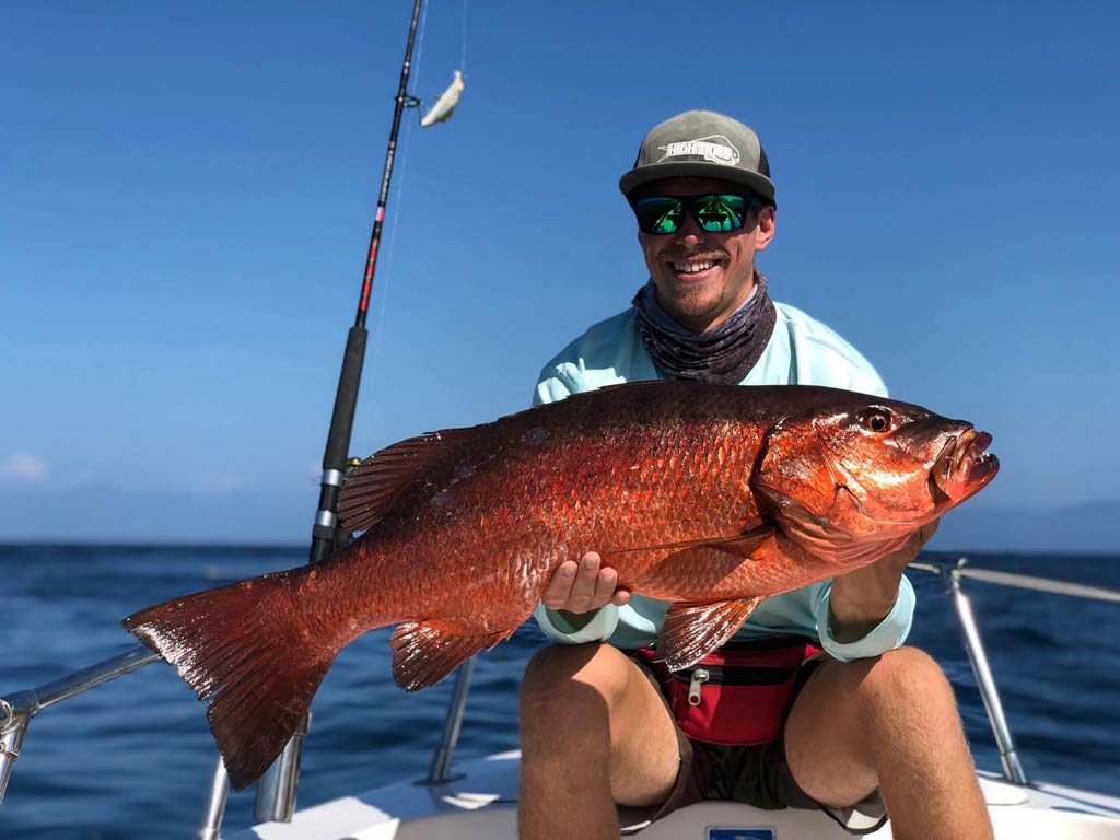 Рыболов , владеющий Cubera Snapper на лодке в Мексике