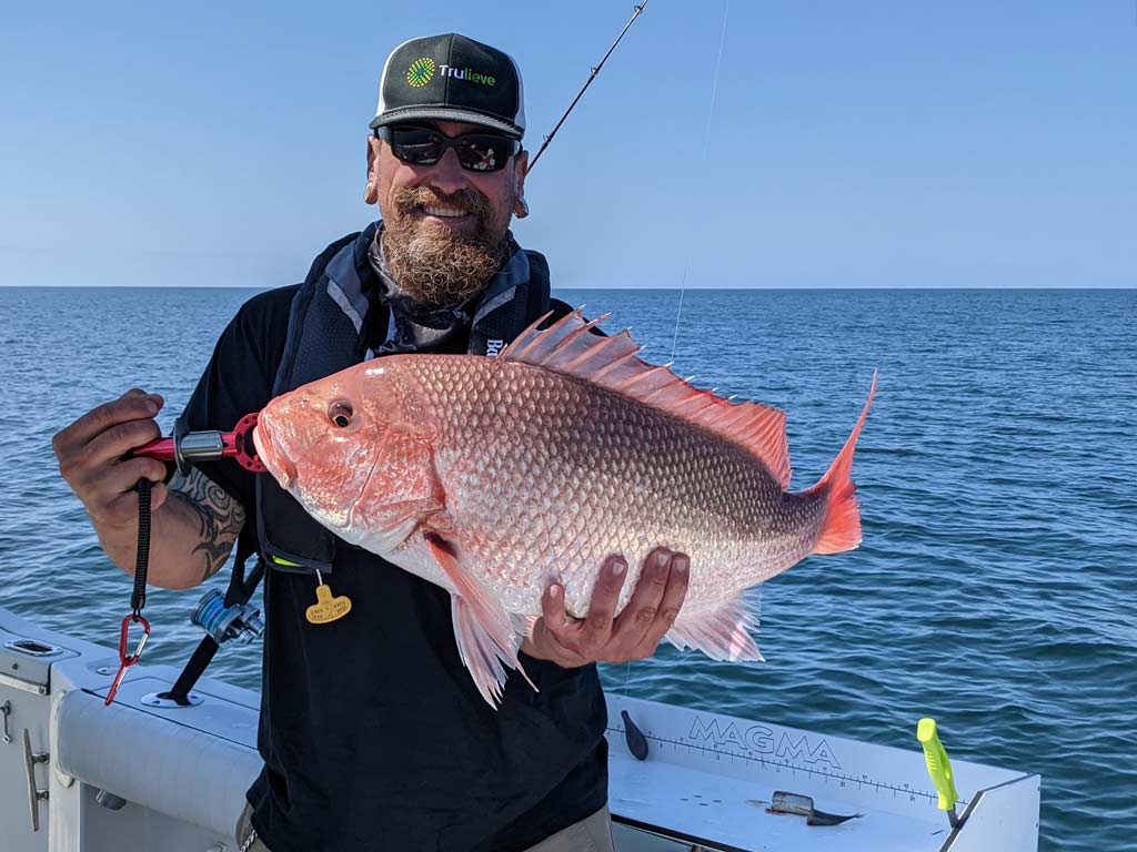 An angler posing with a Red Snapper he caught.