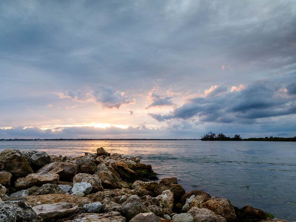 A view of Sebastian Inlet at sunset, with a rock formation from the jetty in the foreground