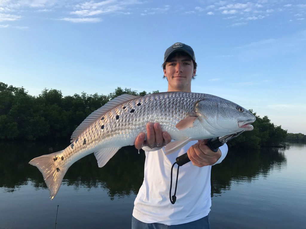 A man holding a big Redfish he caught fishing in Boca Grande, Florida