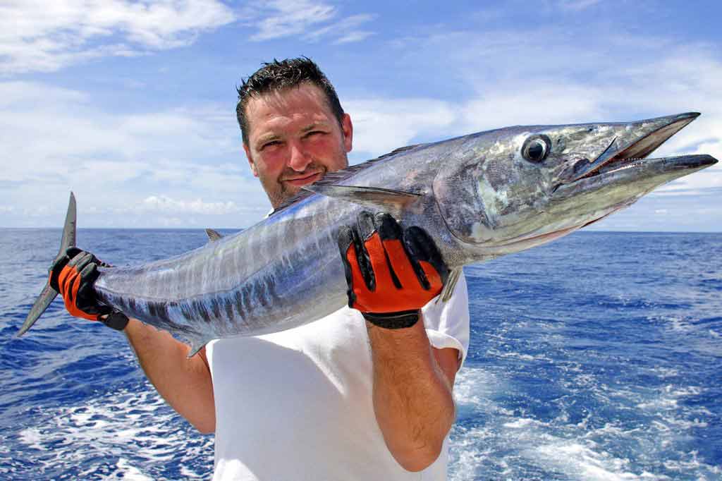 A man holding a Wahoo on a boat