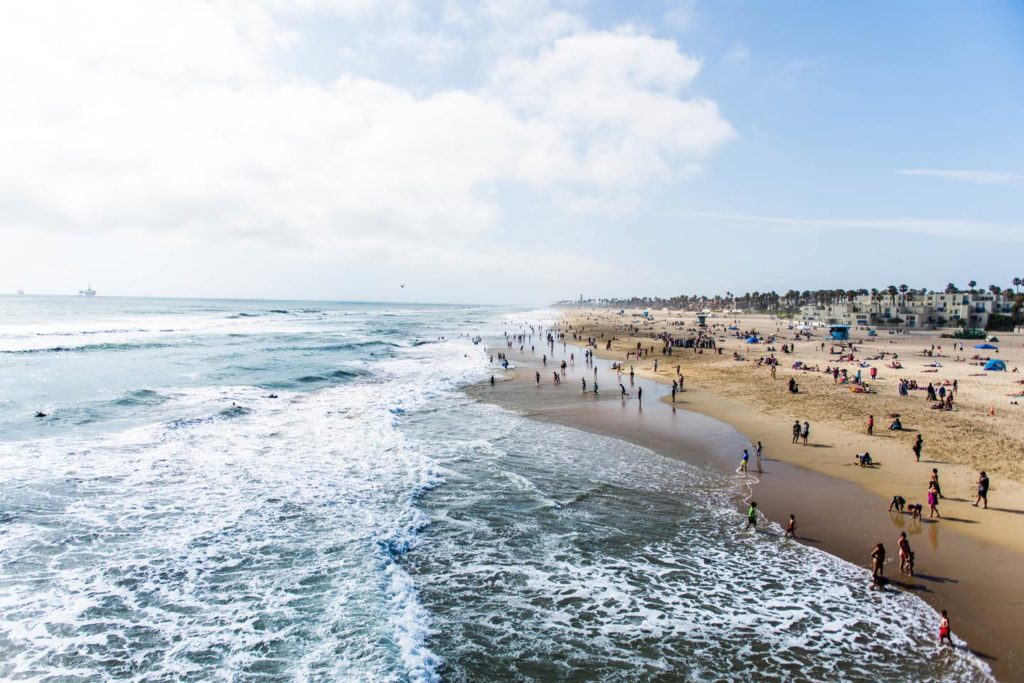 Crowds of tourists and sunbathers having fun in Huntington Beach, California.