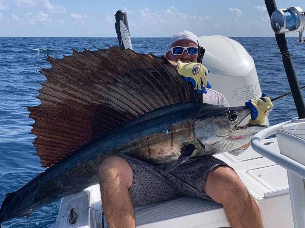 A smiling angler on a boat out of Islamorada holding a large Sailfish