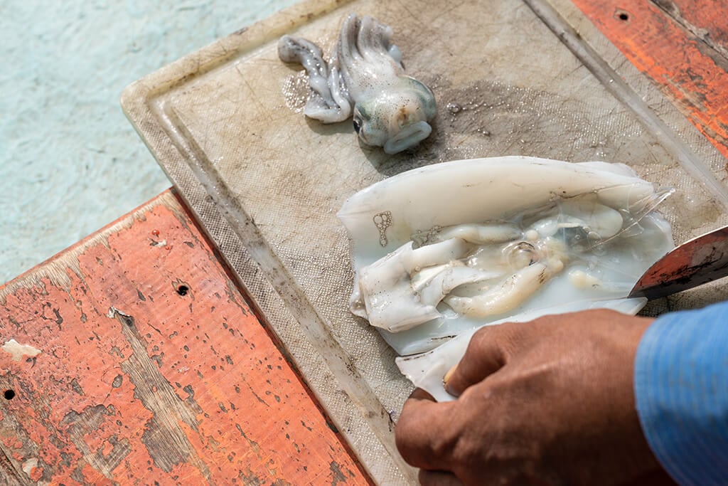 A man cutting up squid to use as bait