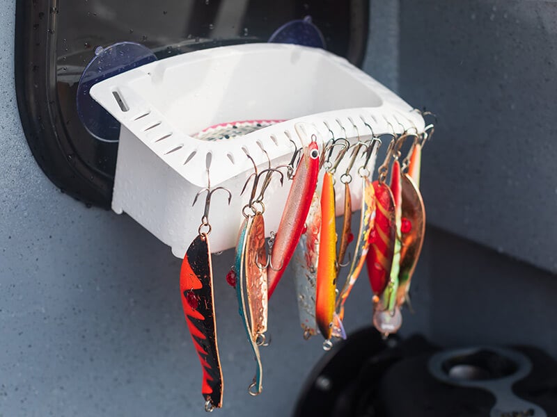 A selection of colorful fishing lures hanging off a white pot