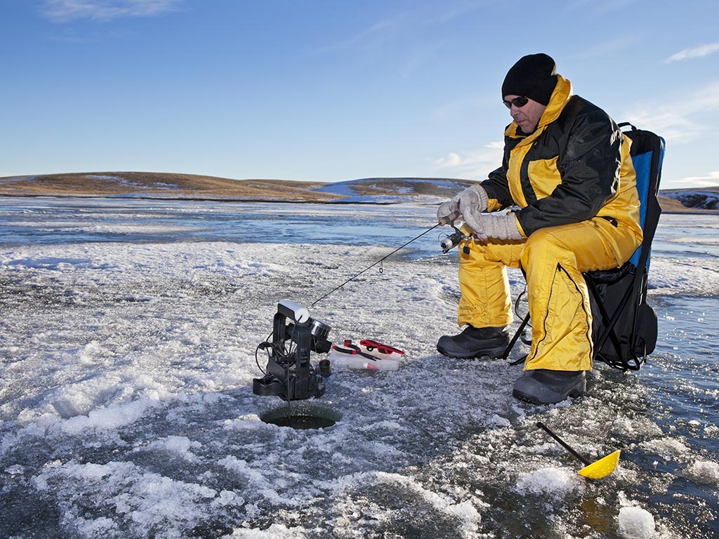 Angler ice fishing on a lake in Canada