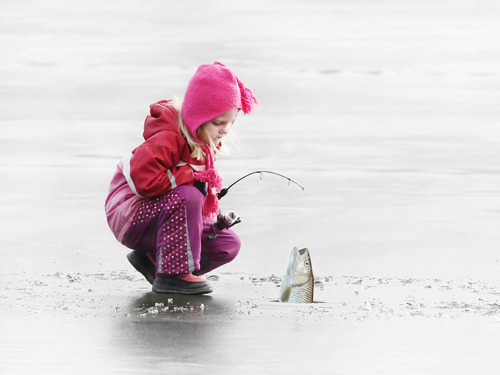 A young girl reels in a fish she caught at a frozen lake in Canada.