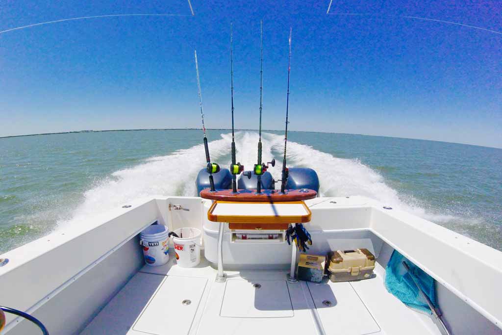 Trolling rods on a boat, with lines in the water, with blue skies in the background