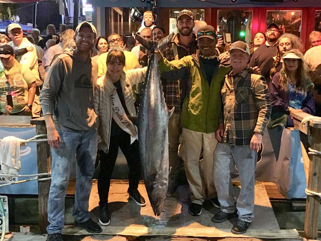 Un grupo de personas se agolpa alrededor de un Kingfish récord capturado durante el rodeo de pesca de Destin