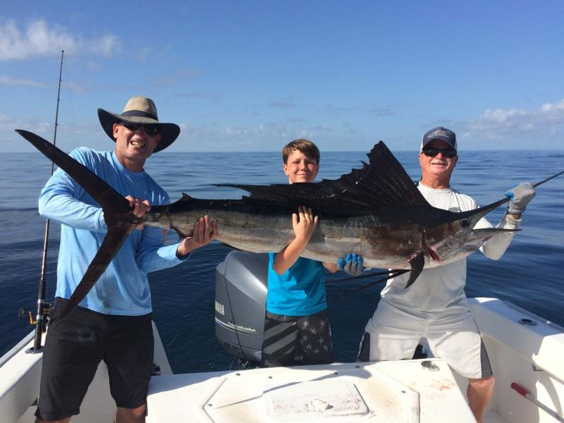 Tres pescadores sostienen un pez vela en la costa de Destin, FL.