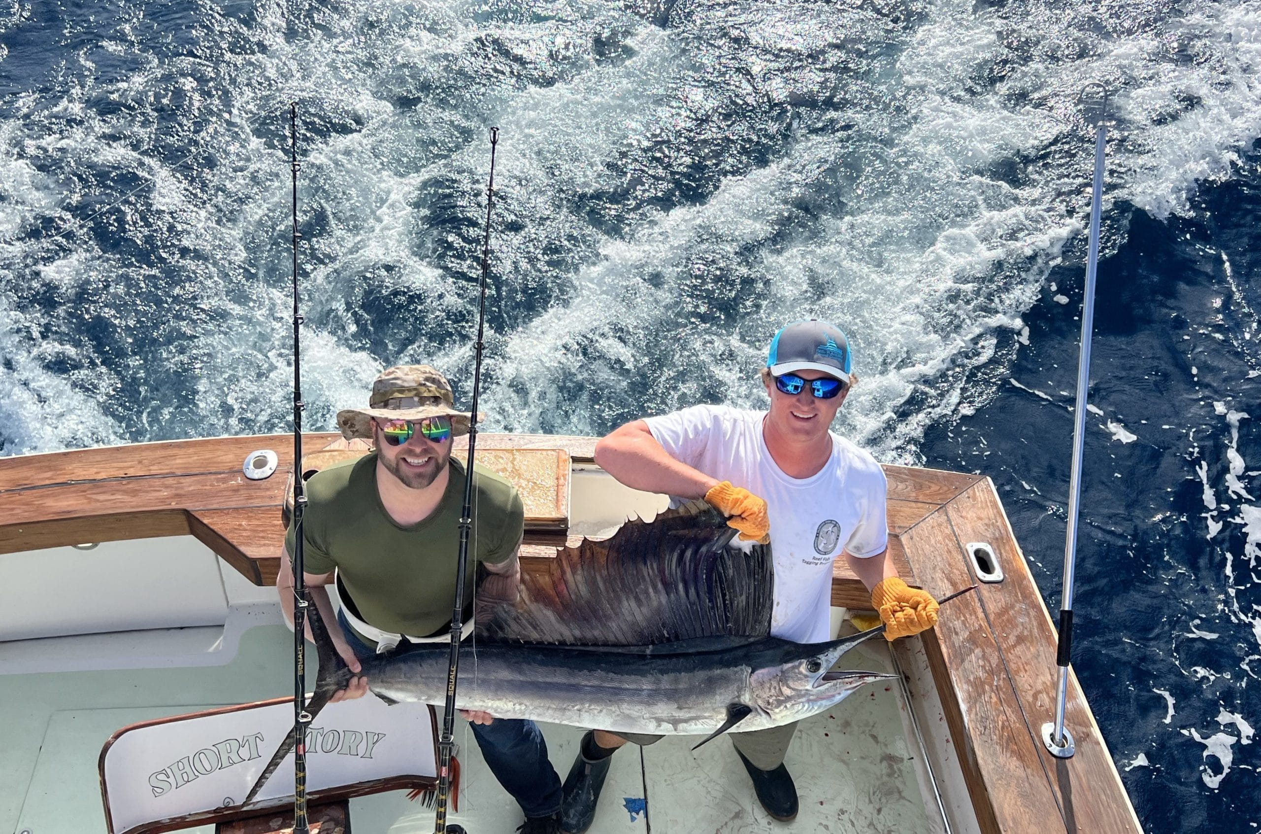 Two anglers holding Sailfish on board Reel Pleasures Fishing Charters in St. Augustine, Florida