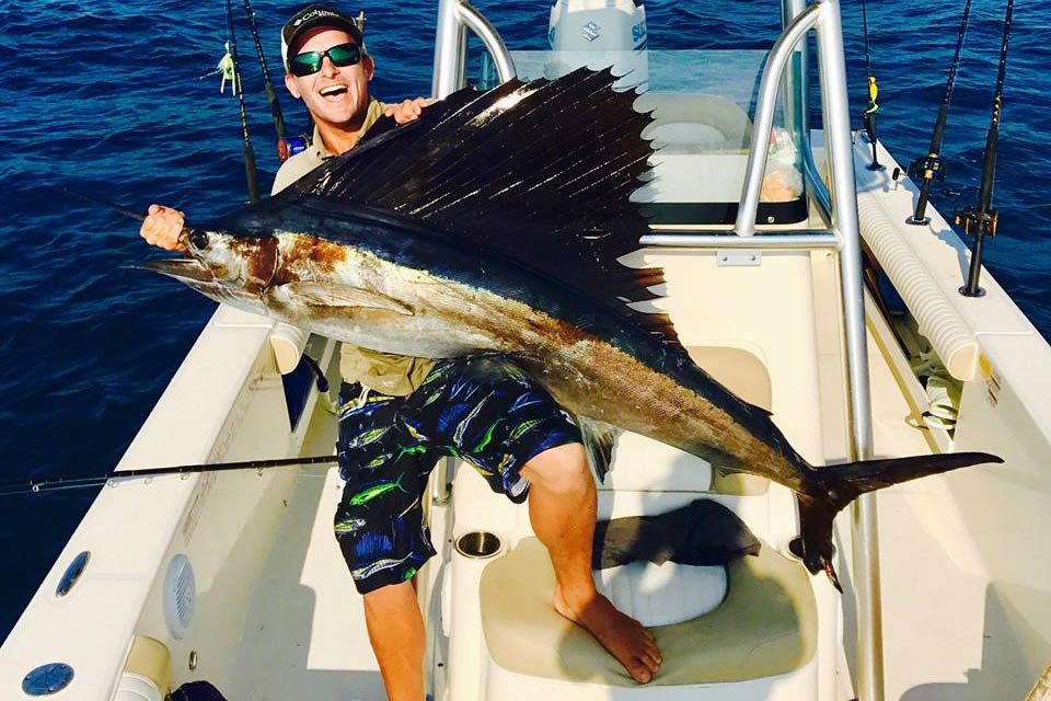 A happy angler holding Sailfish on board First City Fishing Charters, St. Augustine, Florida