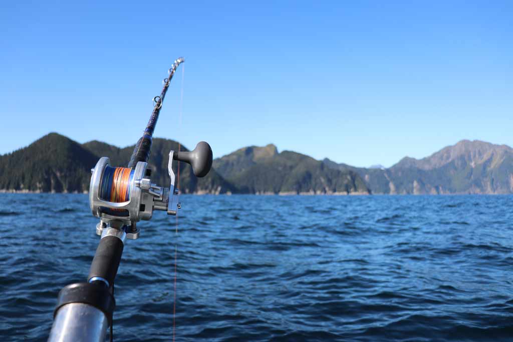 A fishing rod in a holder, on a boat, trolling, with clear skies and water in the background