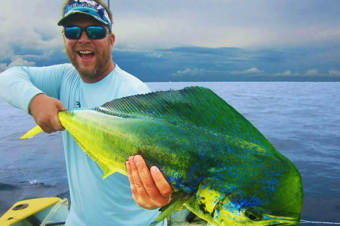 An angler holding a big Mahi Mahi on a boat