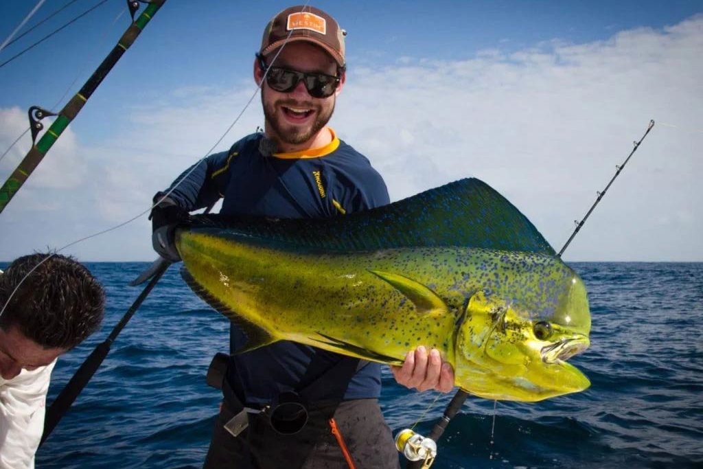 An angler holding a Mahi Mahi on a boat in Cancún