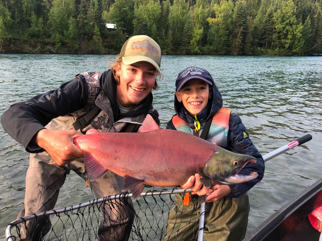 Two anglers holding a Sockeye Salmon they caught fly fishing in Alaska.