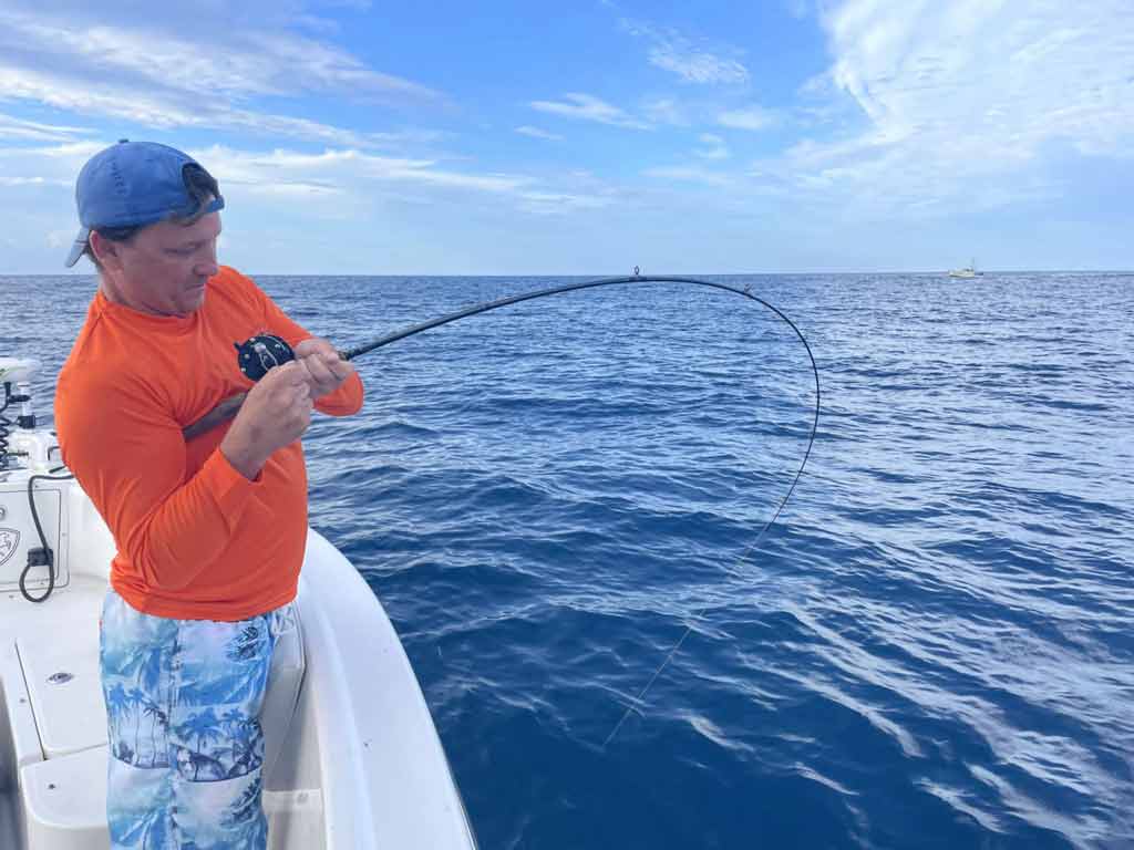 An angler struggling a bit with reeling in a fish from the bottom while deep sea fishing in Daytona Beach, Florida