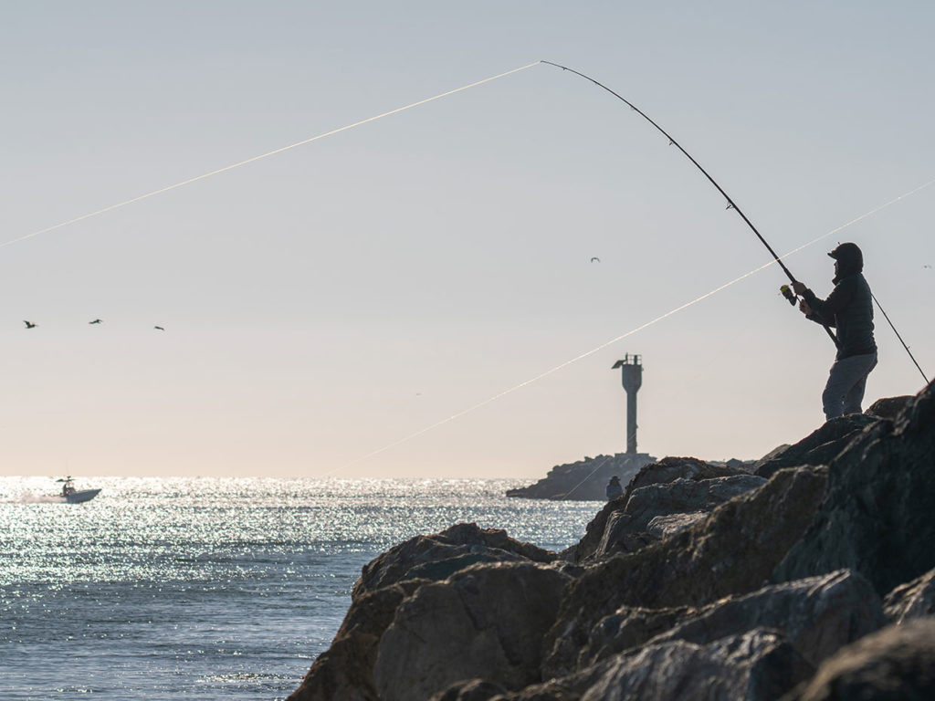 An angler casts a line from the jetty in Half Moon Bay, CA