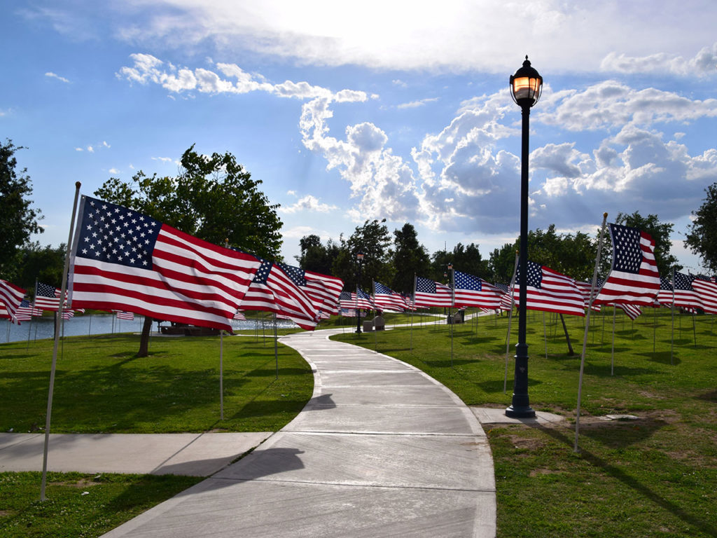 Rows of American flags line a walkway near a river in Bakersfield, CA, for Memorial Day weekend