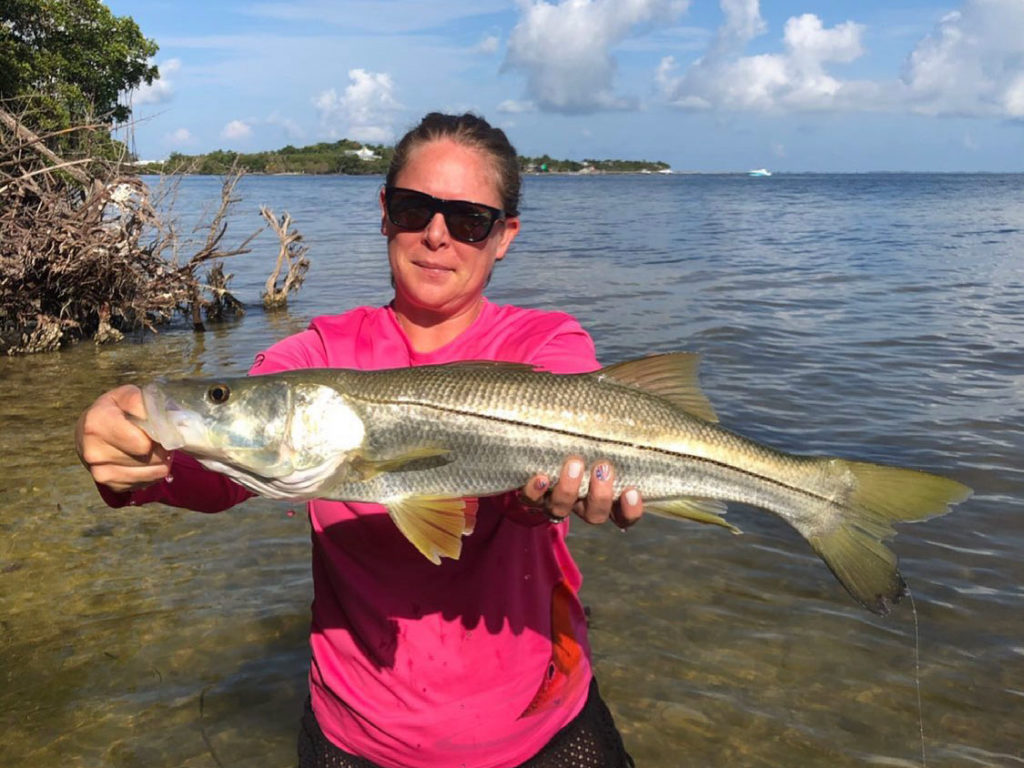 A female angler in the water holding a Snook caught in Cape Coral, FL