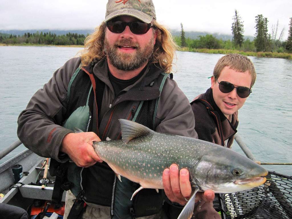 Two anglers on a small boat posing with a trophy-sized Dolly Varden.