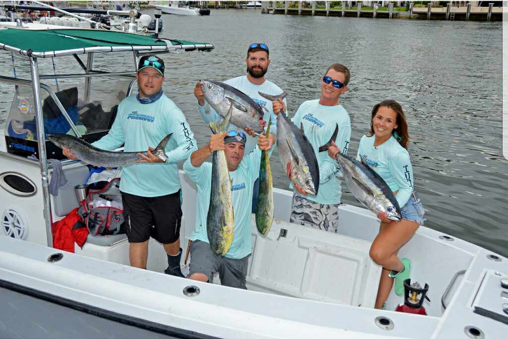 Five anglers standing on a fishing boat with a daily catch of fish