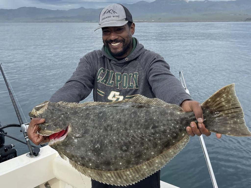 A man posing with a big Halibut he reeled in on a Morro Bay fishing trip.