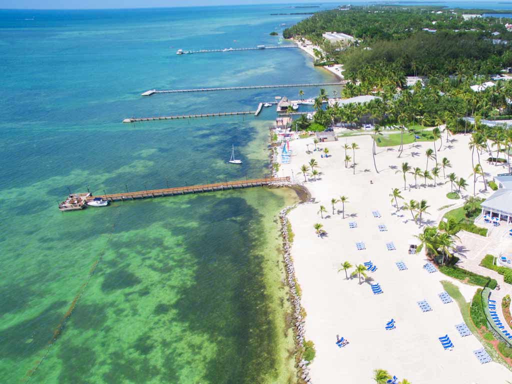 An aerial view of white sand beach, turquoise water, and piers in Islamorada