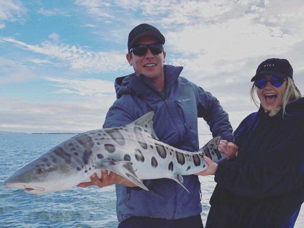 A man and a woman holding a beautiful Leopard Shark.