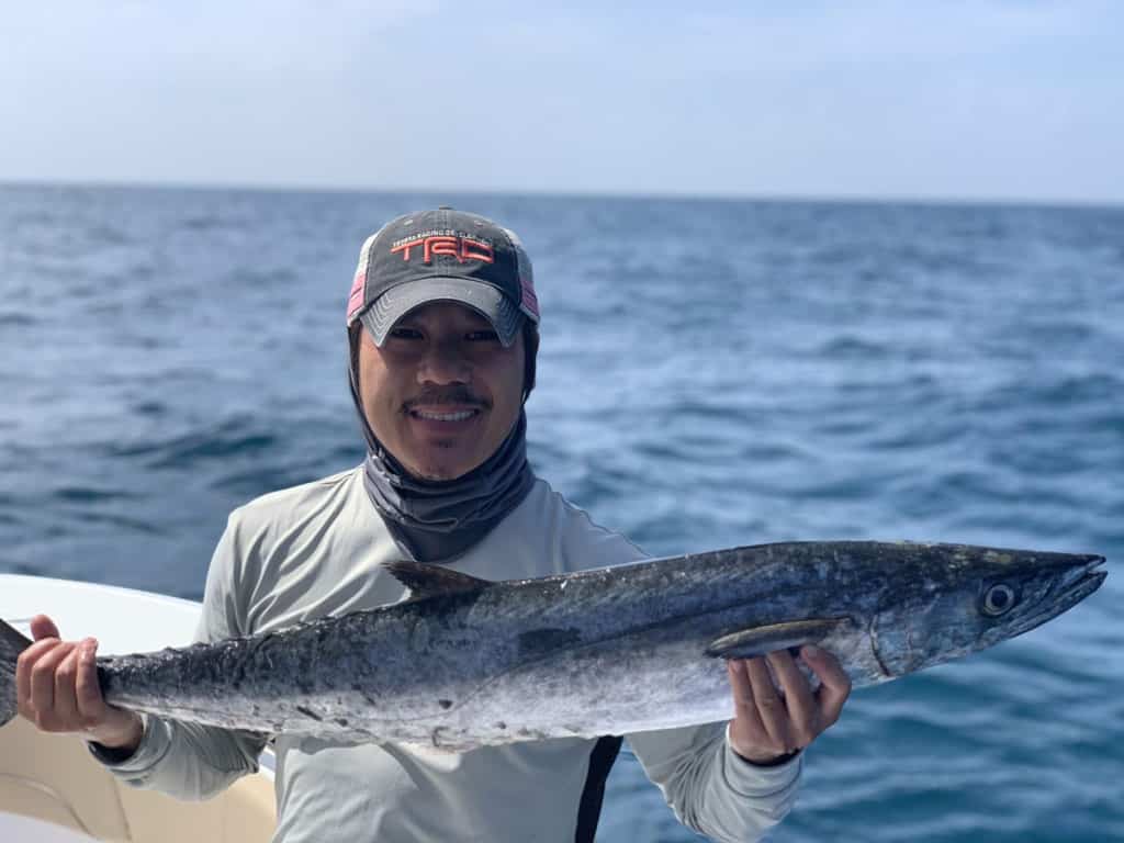 A man posing with a big King Mackerel he reeled in fishing the waters around Tybee Island.