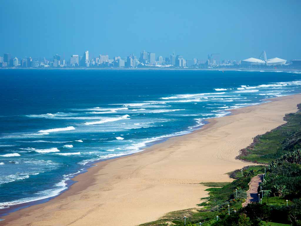 A view of an empty Umhlanga Beach in Durban, with the ocean and city in the distance