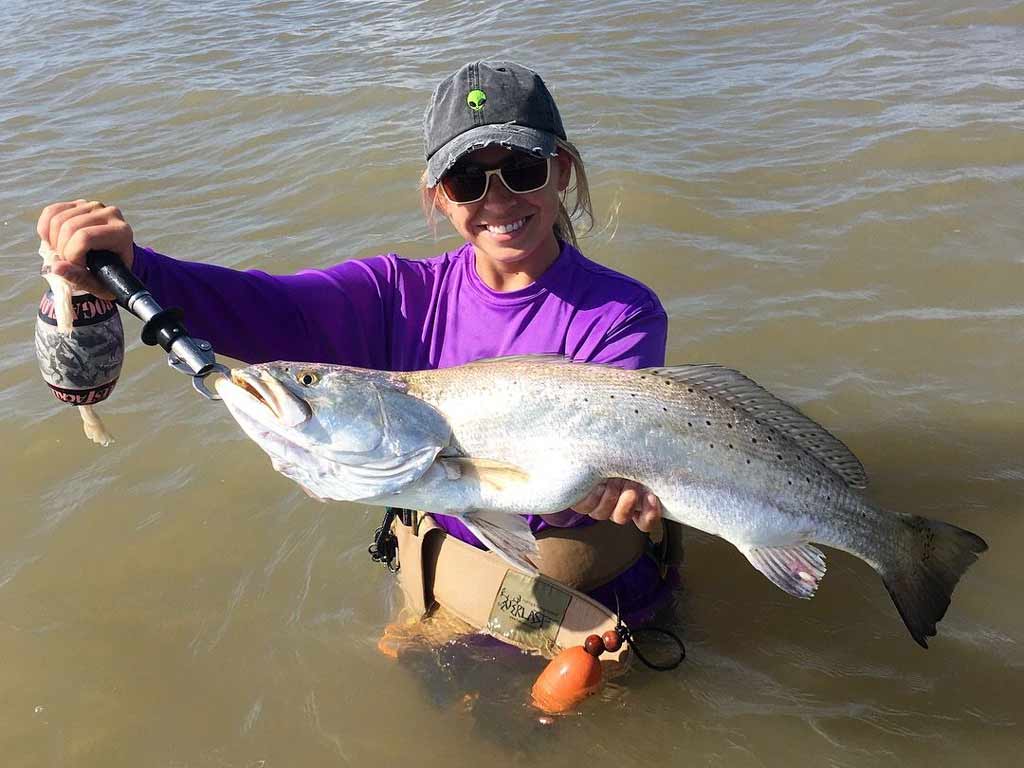 An angler standing in the water and holding big Speckled Trout caught while wade fishing in Port Lavaca