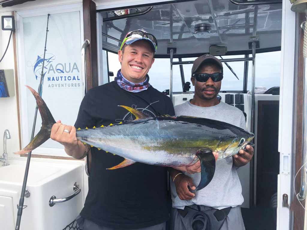 A captain with an angler who is holding Yellowfin Tuna caught while fishing in Durban